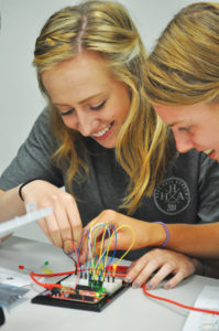 Photo by CAROLINE STELTE Haas Hall Fayetteville seniors Angela Saitta, left, and Hannah Hulbert use wires to make LEDs light up as they learn to build circuits in Introduction to Engineering Design.